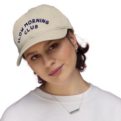 Person wearing a beige cap with 'Slow Morning Club'