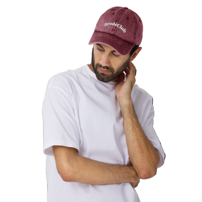 Man wearing a maroon cap with 'BrodeClub' logo on a white background